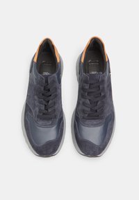 Tumesinised sneakers nahast ja sametist, millel on tekstuuriga pealispind, ümmargune varvas ja kontrastsed oranžid aktsendid kandadel.
