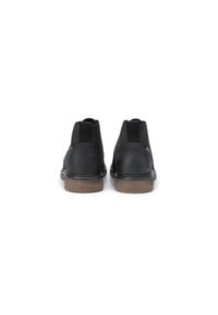 Bottines noires en cuir avec des languettes et une semelle en caoutchouc beige. Elles présentent une texture lisse, des détails cousus et un design minimaliste.