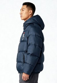 Giacca imbottita blu navy con cappuccio, dotata di cerniera frontale, polsini elasticizzati e grafica bianca di una mano con un cuore rosso sul petto sinistro.