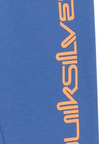 Blauwe sweatshirt van katoen met een oranje logo dat verticaal aan de linkerkant is gedrukt. Zachte textuur, casual ontwerp.