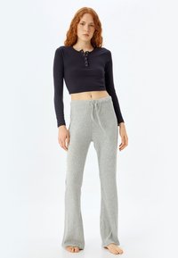 Langsleeve, marineblauw geribbeld crop top met knopen bij de hals, gecombineerd met lichtgrijze geribbelde flared lounge broek met een elastische tailleband.