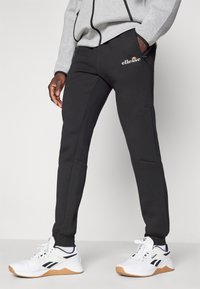 Schwarze Sporthosen mit Slim-Fit, ausgestattet mit Taschen, Logo-Details und gerippten Bündchen. Hergestellt aus einem weichen, langlebigen Stoff.