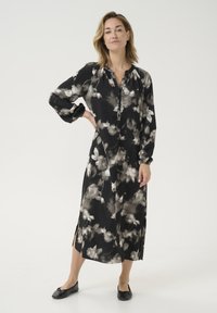 Vestido negro de flores con mangas largas, botón en la parte delantera y aberturas laterales, confeccionado con una tela suave y ligera con acentos grises y un ajuste relajado.