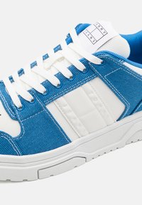 Sneaker blu e bianchi con una trama in denim, suola in gomma e lacci bianchi. Presenta il marchio sul lato e una linguetta imbottita.