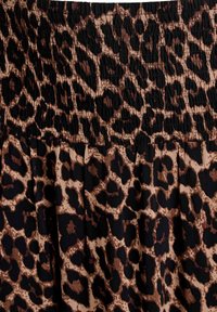 Tejido con estampado de leopardo y una textura suave, que presenta una combinación de colores negro y marrón claro. Cintura elástica con fruncido y pliegues fluidos.
