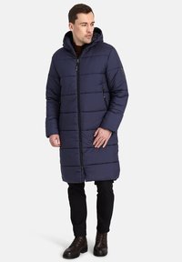 Cappotto imbottito blu navy con cappuccio, dotato di sezioni a righe orizzontali, tasche laterali con zip e chiusura frontale con zip.