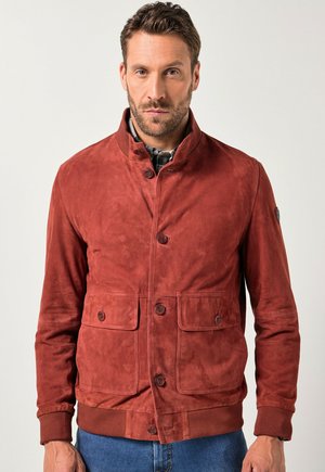 Chaqueta de ante en color naranja óxido con un cuello alto y dos bolsillos frontales. Presenta cierre de botones y puños y dobladillo acanalados.