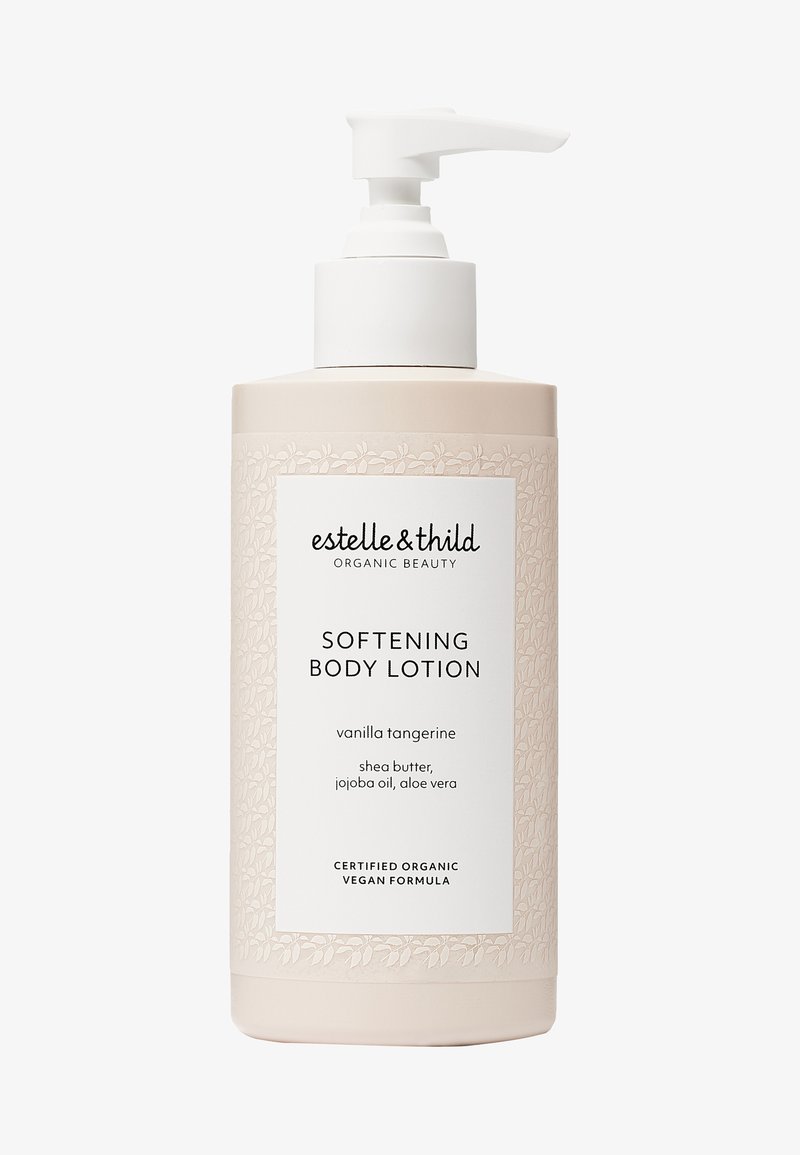 Pumpet flaske med mykgjørende kroppslotion, lys rosa med blomstermønsterdetaljer. Hvit etikett med teksten "vanilje mandarin", inneholder shea-smør, jojobaolje og aloe vera.