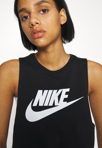 Top in cotone senza maniche di colore nero con logo Nike bianco sul petto. Caratterizzato da un collo rotondo e una vestibilità standard.