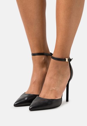 Escarpins noirs à talons hauts avec bout pointu, bride à la cheville et finition en cuir brillant. Talon aiguille avec détail de surface texturée.