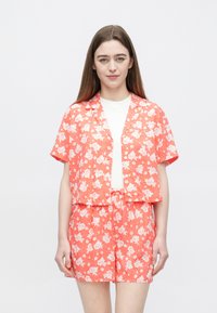 Krótki rękaw, koralowa bluzka w kwiaty z białymi kwiatami, zestawiona z pasującymi szortami. Lekka tkanina, casualowy design, luźny krój.