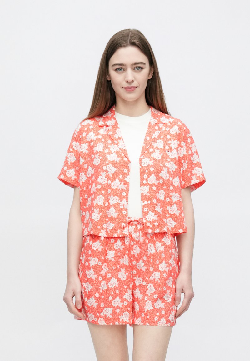 Krótki rękaw, koralowa bluzka w kwiaty z białymi kwiatami, zestawiona z pasującymi szortami. Lekka tkanina, casualowy design, luźny krój.