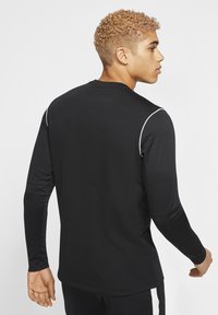 Zwart sportshirt met lange mouwen, voorzien van witte accentstiksels, een gladde textuur, een ronde hals en een aansluitend ontwerp voor comfort tijdens beweging.