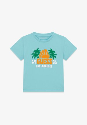 Chemise bleu clair à manches courtes avec un soleil orange, des palmiers verts et le texte « 1981 GUESS LOS ANGELES » sur le devant.