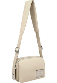 Beige crossover-veske laget av glatt materiale, med glidelås, justerbar stropp og preget logo på fronten.