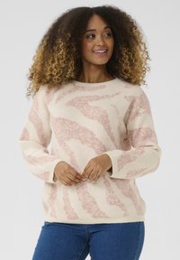 Krämfärgad tröja med rosa abstrakt mönster; rund halsringning, långa ärmar och ribbade muddar; tillverkad av mjukt, strukturerat tyg.