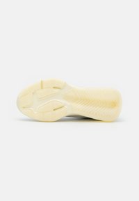 Shoe outsole featuring a textured rubber surface in cream color with zigzag and herringbone patterns for traction and grip.