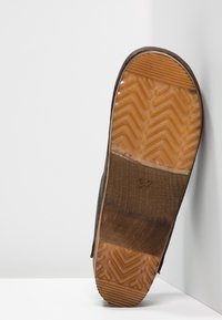 Brun gummisula sko med en strukturerad fiskbensmönster, med en slät läderöverdel och storleksmärkning "37" på sulan.