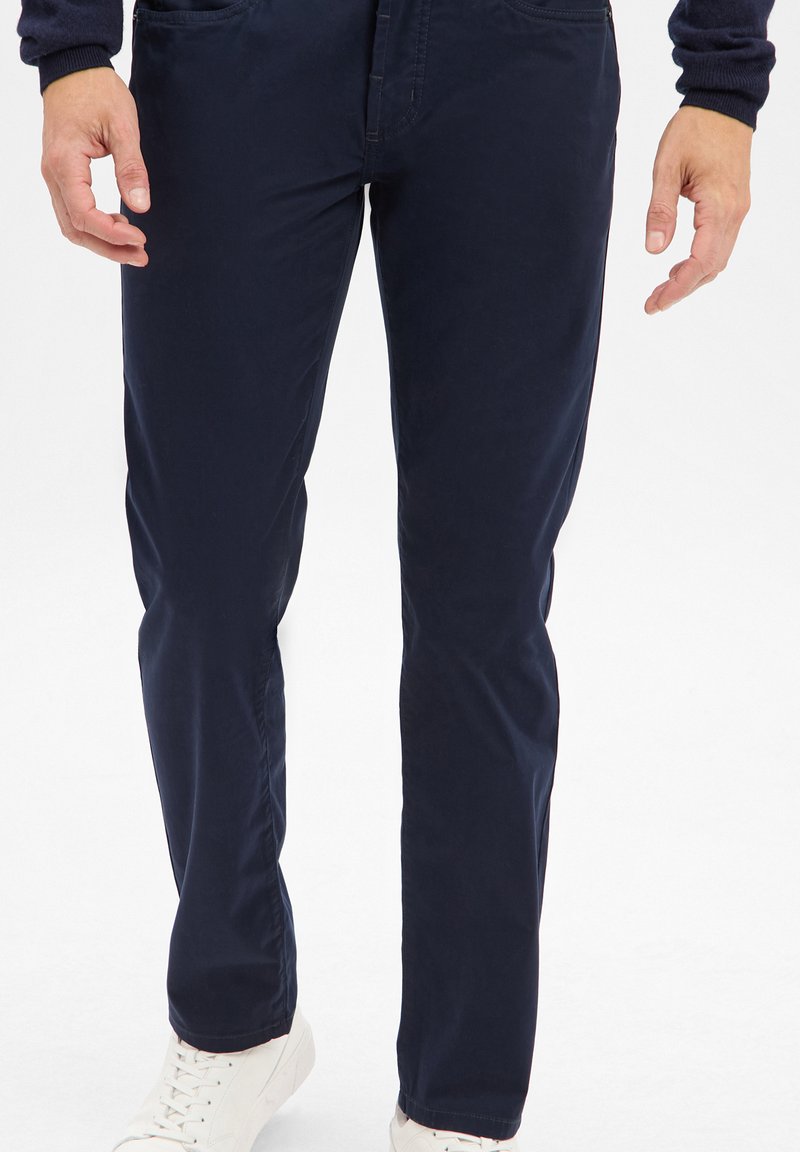 Granatowe chinosy wykonane z mieszanki bawełny, charakteryzujące się slim fit, dwoma przednimi kieszeniami i gładką teksturą, zestawione z białymi trampkami.