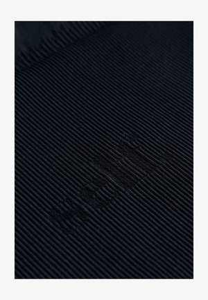 Tummansininen resorikangas, jossa on teksturoitu pinta. Sisältää hienovaraisen kohopainetun logon tai kuvion. Materiaali vaikuttaa pehmeältä ja kestävältä.