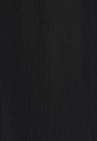 Schwarzer strukturierten Stoff mit feinen vertikalen Linien. Das Material erscheint leicht und leicht transparent und bietet eine subtile visuelle Komplexität.