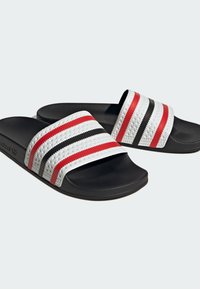 Sandali neri con sole in gomma testurizzata, caratterizzati da tre strisce orizzontali in rosso, nero e bianco su una tomaia bianca.