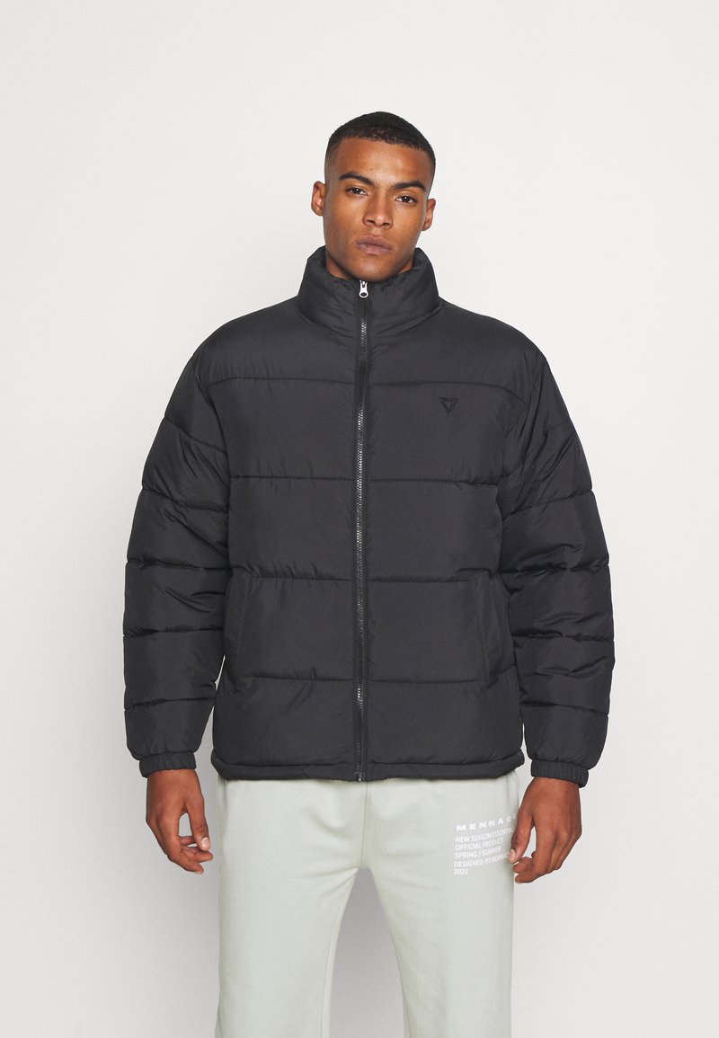 Schwarze Steppjacke mit hohem Kragen, Reißverschluss und gestepptem Design. Verfügt über eine weiche Textur und ein Logodetail auf der Brust.
