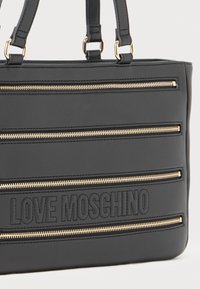 Schwarze synthetische Tote-Tasche mit goldenen Reißverschlussakzenten und geprägt "LOVE MOSCHINO" Logo. Strukturierte Form mit doppelten Griffen zum Tragen.
