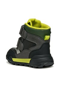 Bota de tobillo para niño que combina ante gris y malla con un acento verde, dos correas de Velcro y una suela de goma negra texturizada.