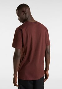 Burgundy puuvillainen t-paita lyhyillä hihoilla, pyöreä kaula-aukko ja rento leikkaus, esillä takaa, paljastaen sileän pinnan.