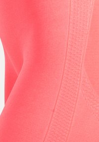 Helles Korallen-Sportgewebe mit glatter Textur und einem Mesh-Akzentstreifen. Verfügt über geschwungene Nähte für eine ergonomische Passform.