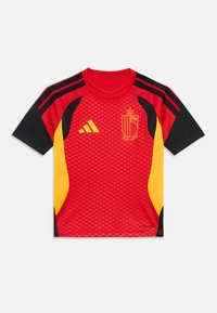 Κόκκινη και μαύρη αθλητική φανέλα με κίτρινες λεπτομέρειες, διαθέτει υφή, κοντά μανίκια και το εθνόσημο μπροστά.