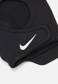 Black neoprene brace with a rounded opening, featuring visible stitching and a white Nike logo, designed for support and stability.