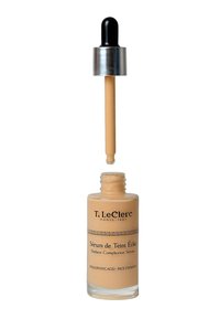Strahlendes Teint-Serum in einer klaren Glasflasche, enthält eine beige Flüssigkeit und einen schwarzen Tropfer mit silbernen Akzenten, etikettiert mit Markendetails.