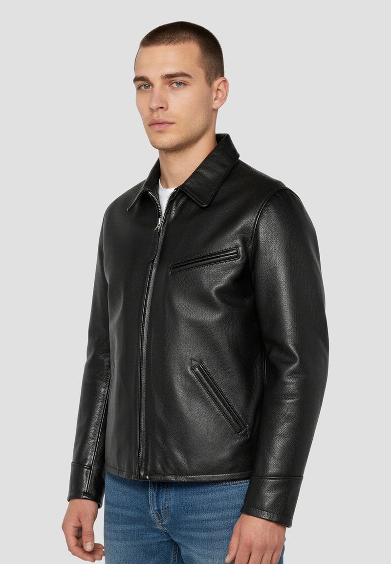 Veste en cuir noire avec un col à revers, deux poches latérales et une texture lisse. Fermeture éclair à l'avant, coupe cintrée.