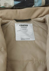 Beige isolierte Jacke mit weichem Innenfutter. Verfügt über ein weißes Etikett, das die Marke "Reima", die Größe "92 / 2T" und Pflegehinweise anzeigt.