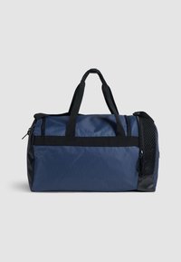 Bolsa de lona marina con acentos negros, compartimento principal con cremallera, dos asas y bolsillo lateral de malla. Tejido duradero con una superficie texturizada.