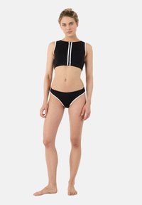 Costume da bagno due pezzi nero con top corto senza maniche dotato di zip frontale e dettagli bianchi, abbinato a slip a vita alta coordinati.