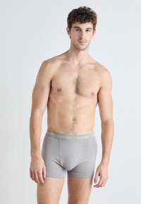 Boxer da uomo in cotone grigio con waistband logo Calvin Klein, caratterizzati da una vestibilità aderente e una superficie liscia. Modello in posizione frontale.
