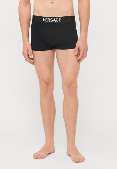 Sorte bomulls_boxershorts med bred svart linning som har den hvite "VERSACE"-logoen. Tett passform med en glatt tekstur.