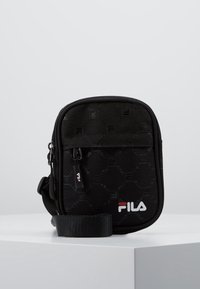 Czarna torba na ramię Fila z sześciokątnym wzorem, zamkiem błyskawicznym i regulowanym paskiem. Na dole znajduje się biało-czerwone logo.