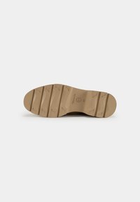 Semelle de chaussure en caoutchouc beige, avec un motif de traction texturé, un embout arrondi et un branding discret. Taille 41 indiquée sur le talon intérieur.