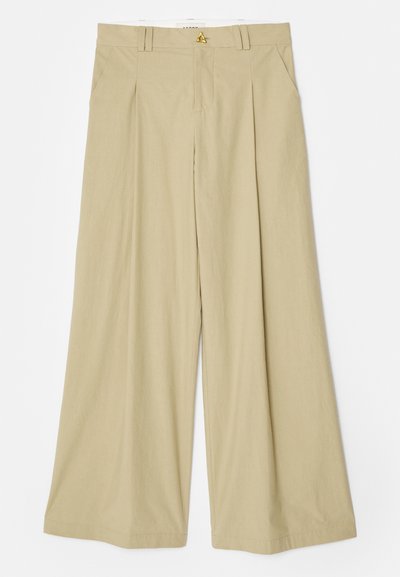 Kreemivärvilised laia jalgadega püksid, mis on valmistatud kergest kangast. Omavad lapikut esiosa, kahte külgtaskut ja kuldse triiksuuna aktsenti vööl.