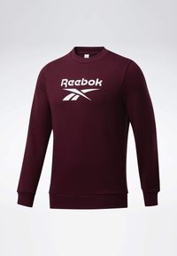Sweat-shirt bordeaux à manches longues avec col rond et logo blanc Reebok centré sur la poitrine sur un fond uni.