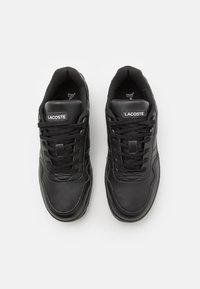 Czarne skórzane trampki o gładkim wykończeniu, z wiązanym zapięciem, wyściółką w kołnierzu oraz metką z logo na języku. Widoczna wkładka Ortholite®.