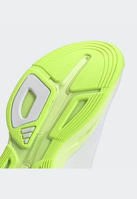 Schuhsohle aus grünem und weißem Gummi, mit strukturierten Mustern und Rillen für besseren Halt. Das Design ist leicht und flexibel.