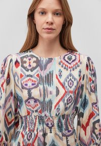 Maxi-Kleid mit bunten abstrakten Mustern in Rot, Blau und Lila. Geraffte Taillendetails, lange Puffärmel, weicher Stoff.