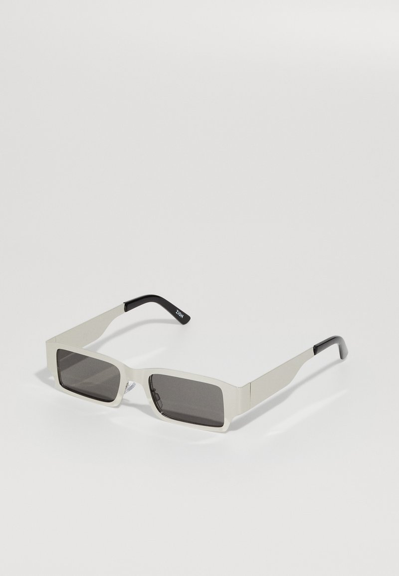 Rechteckige Sonnenbrille mit einem hellgrauen Rahmen und dunkelgrauen Gläsern. Sie verfügt über schmale Bügel mit einem schwarzen Akzent. Insgesamt glatte Oberfläche.