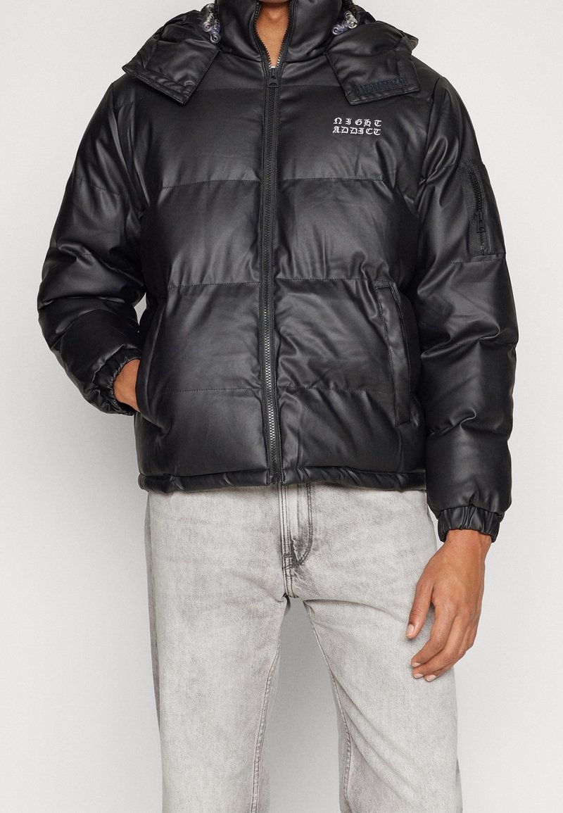 Czarna kurtka puchowa z błyszczącym wykończeniem, z zamkiem z przodu, regulowanym kapturem, elastycznymi mankietami i logo na piersi. Teksturowany, pikowany wzór.