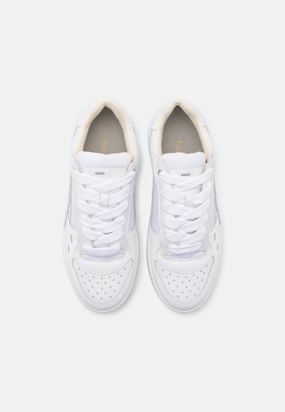 Weiße Sneakers mit einem Obermaterial aus glattem Leder und Mesh-Akzenten, ausgestattet mit runden Perforationen, flachen Schnürsenkeln und einer gepolsterten Innensohle.